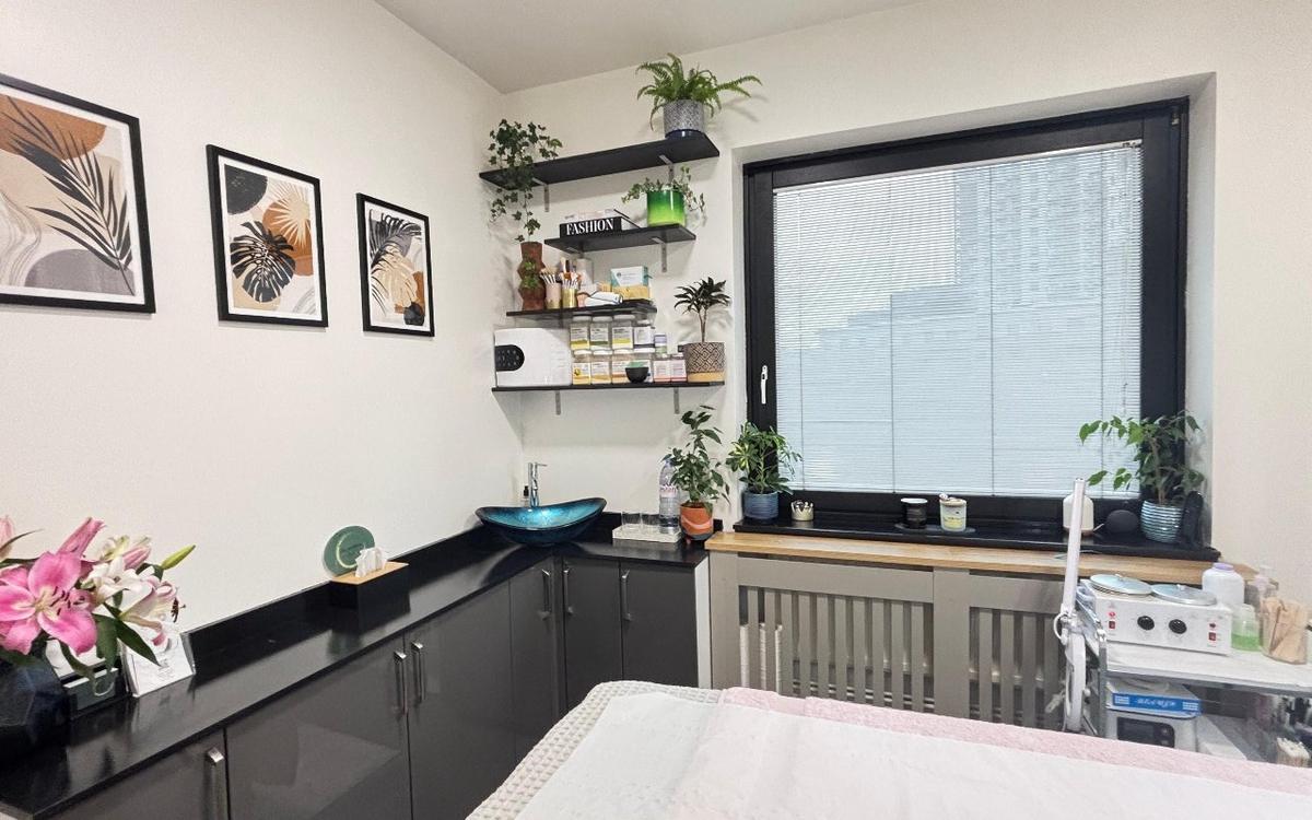 Calm corner of the studio with plants, professional products on the shelves and a bright window